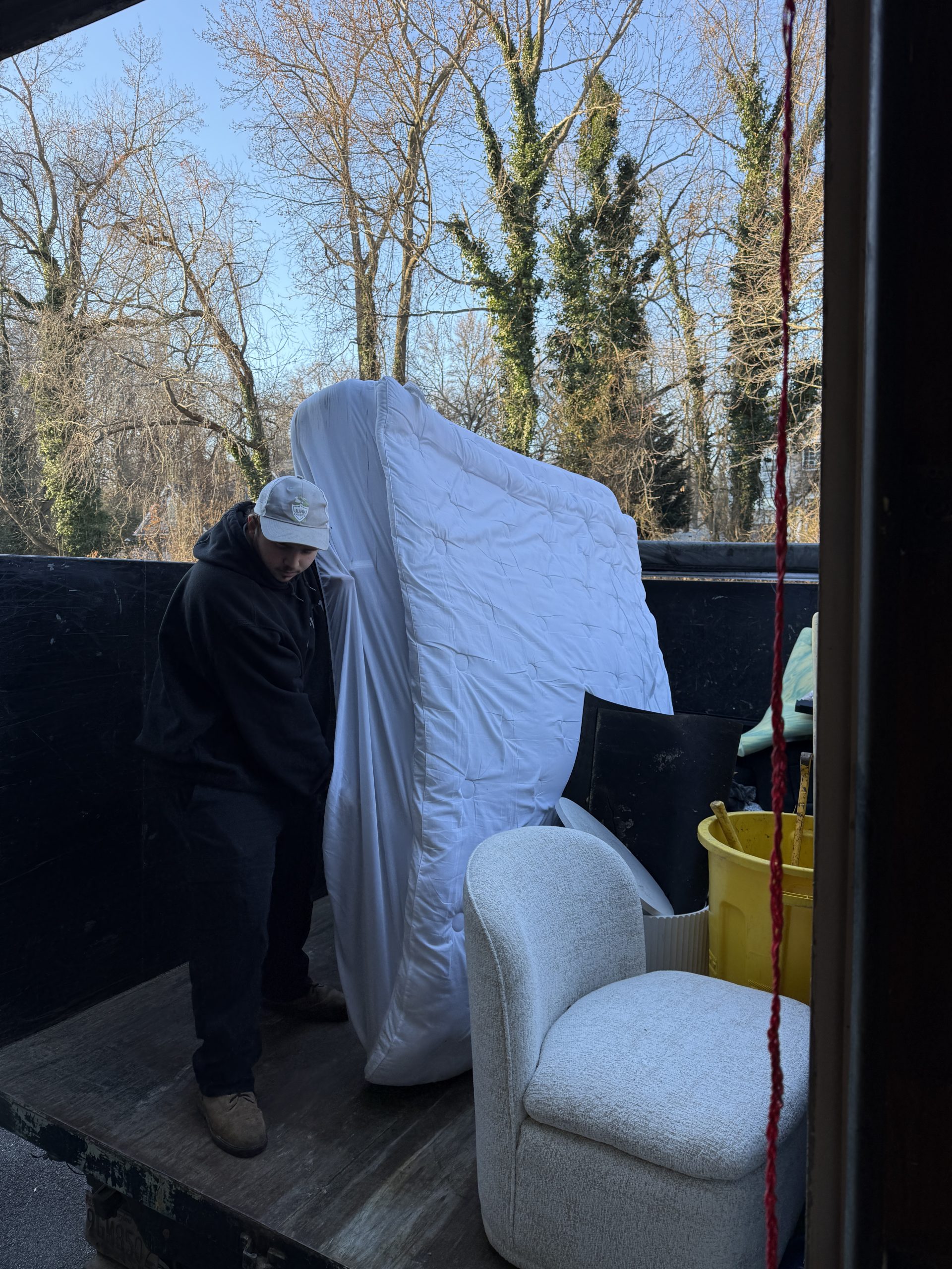 Brayden loading a mattress into the Junk Knights truck